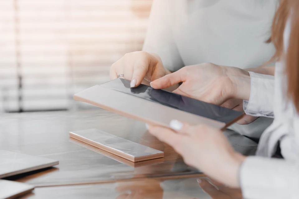 Homme en extérieur découpant des carreaux de carrelage blanc sur pelouse avec meuleuse d'angle électrique